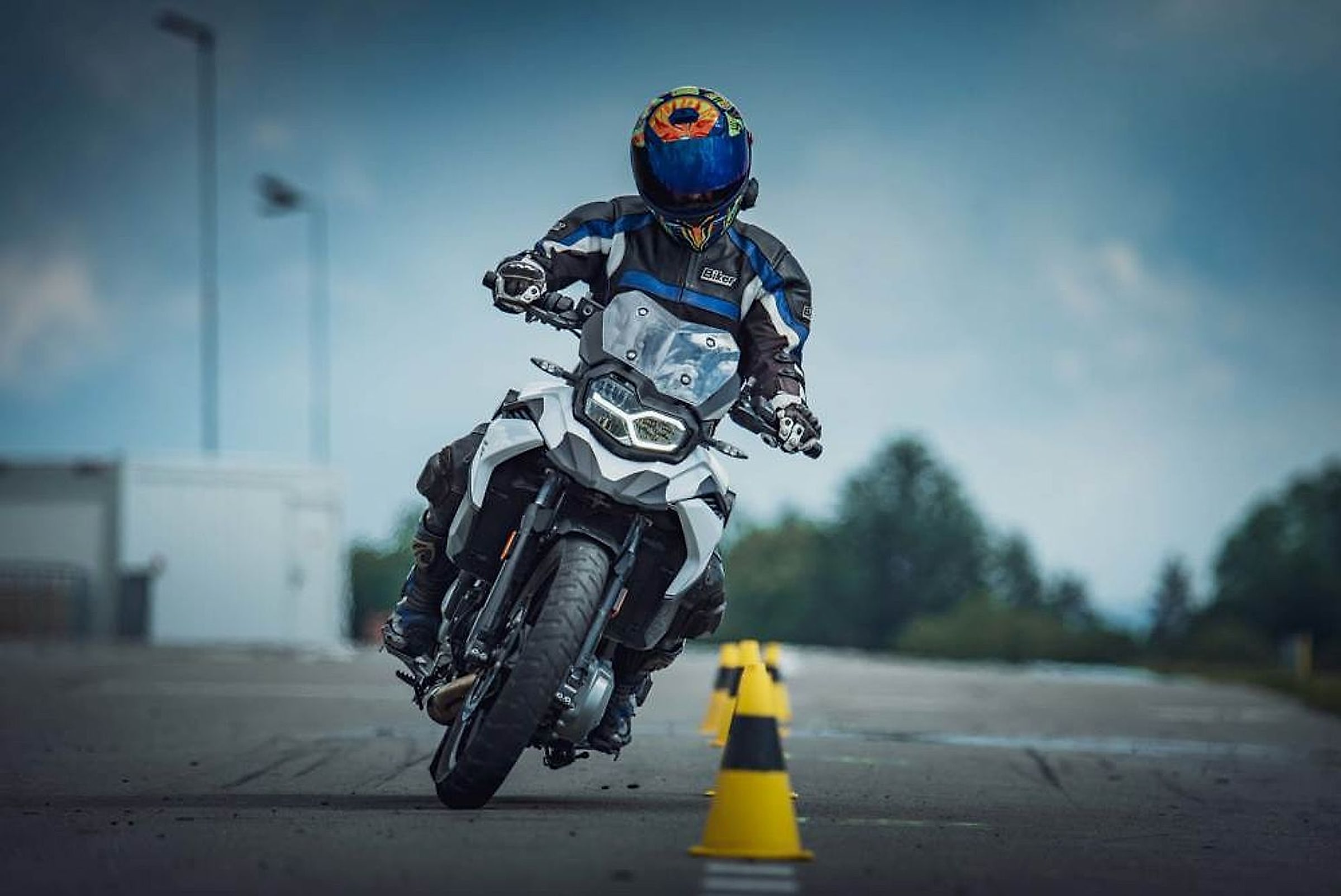 Jezdec v hlubokém náklonu kolem kužele při dovednostním cvičení na motorce BMW