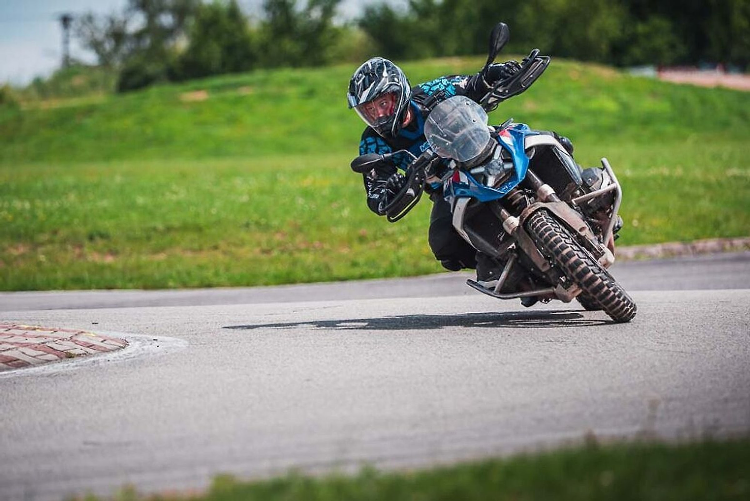 Jezdec na BMW GS se v náklonu opírá do zatáčky asfaltového okruhu