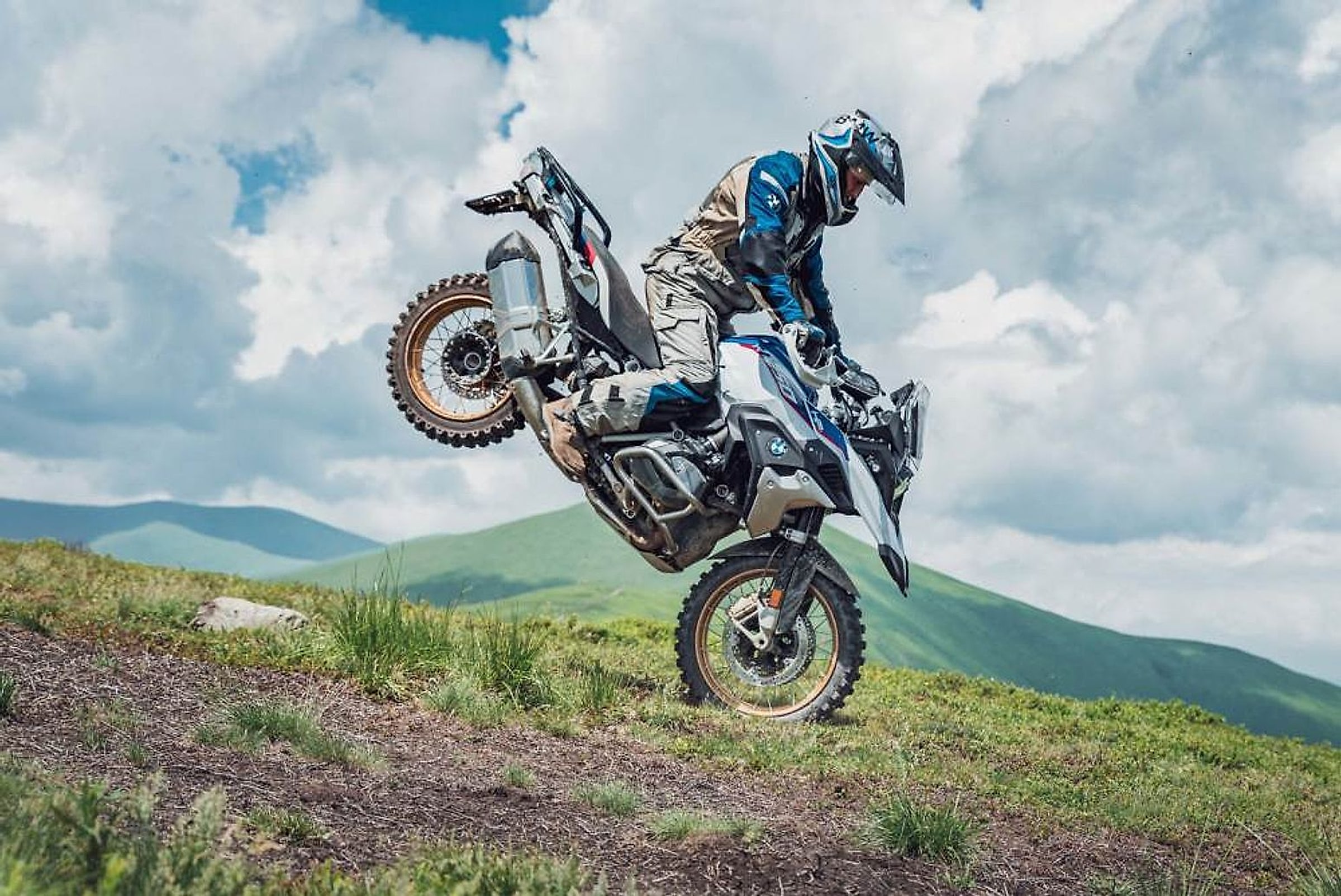Jezdec na BMW R 1250 GS vytahuje přední kolo na horské louce na Ukrajině