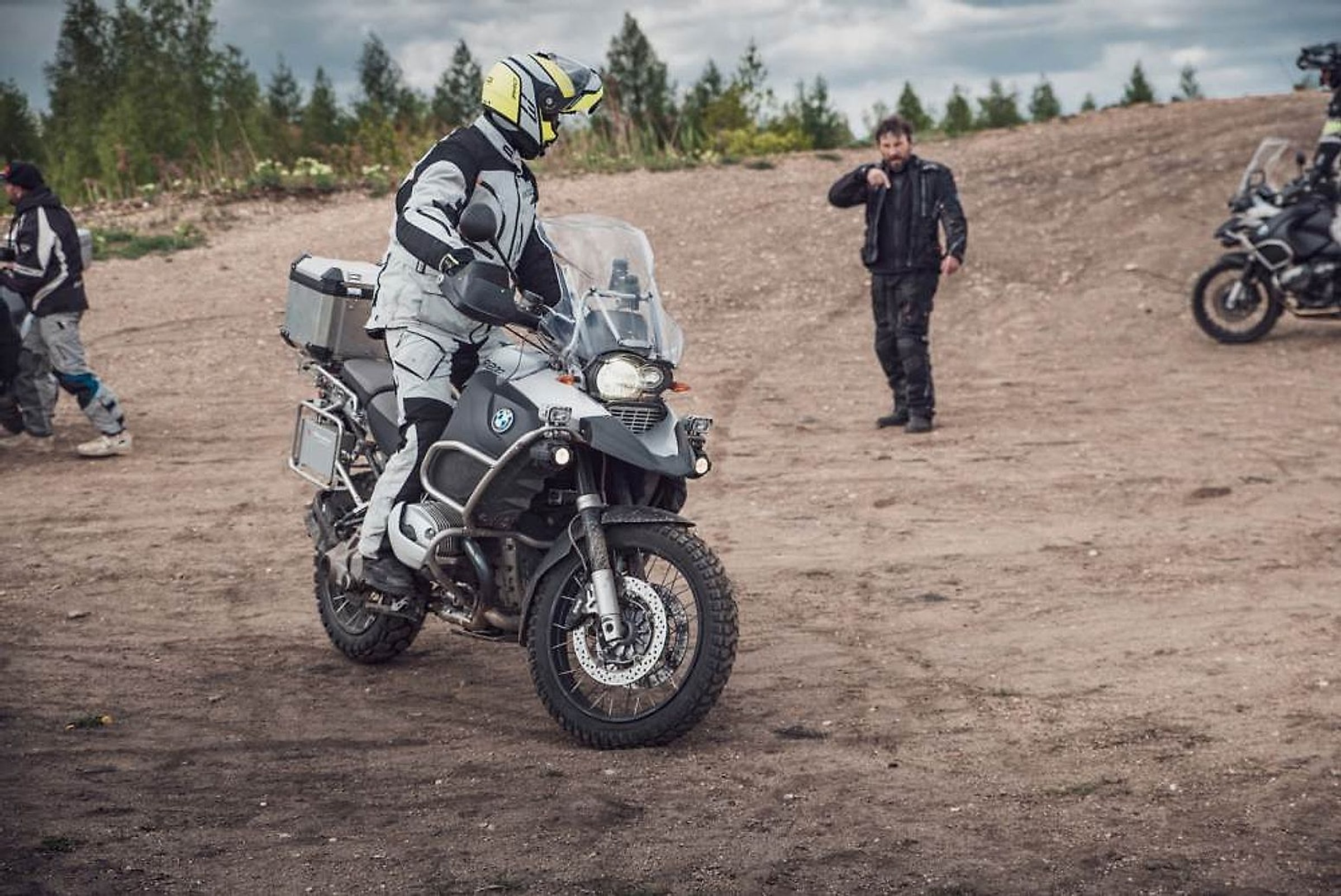 Jezdec na BMW GS s kufry na výcvikové ploše, instruktor sleduje jeho jízdu