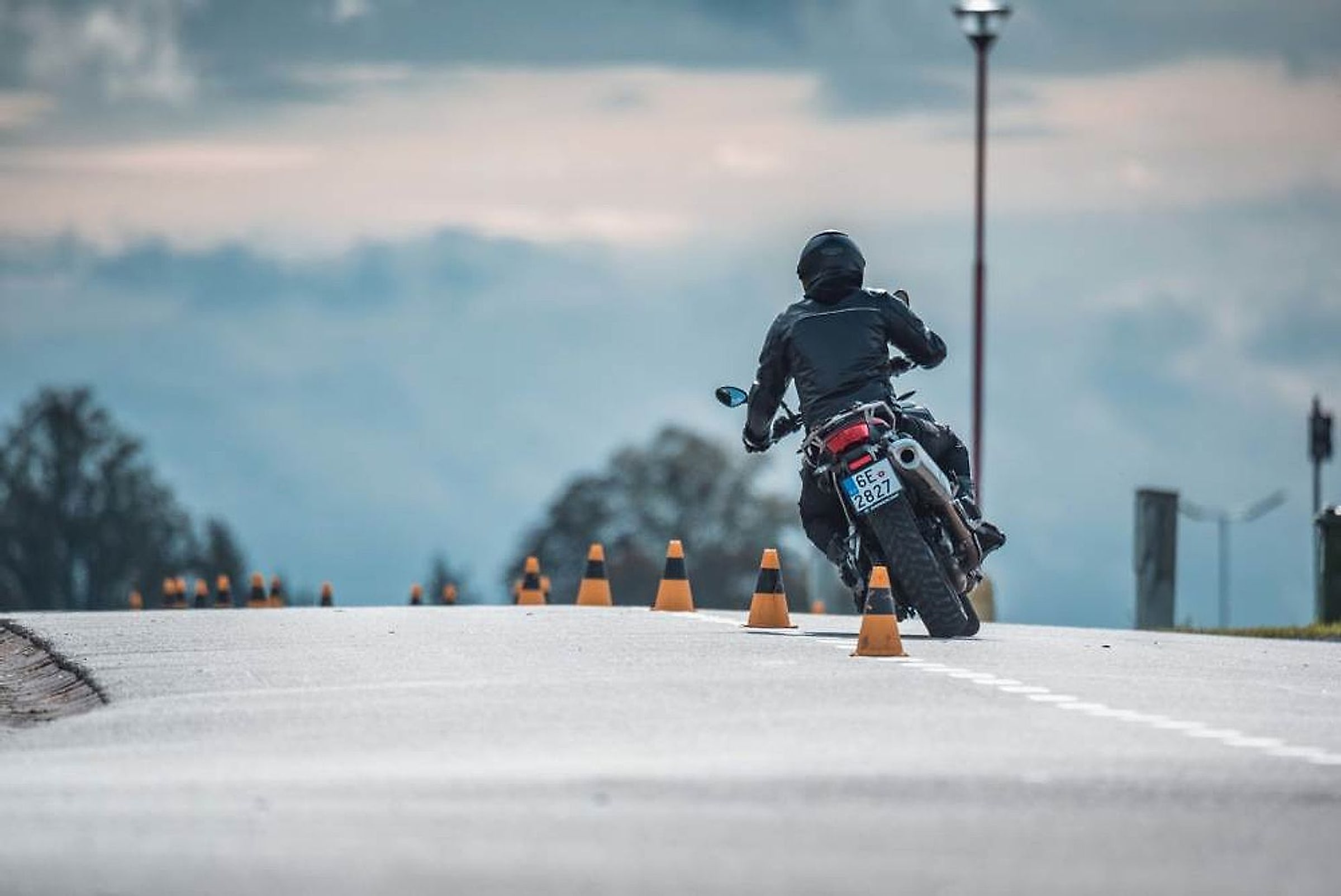 Motorkář na okruhu projíždí mezi kužely při nácviku úhybného manévru