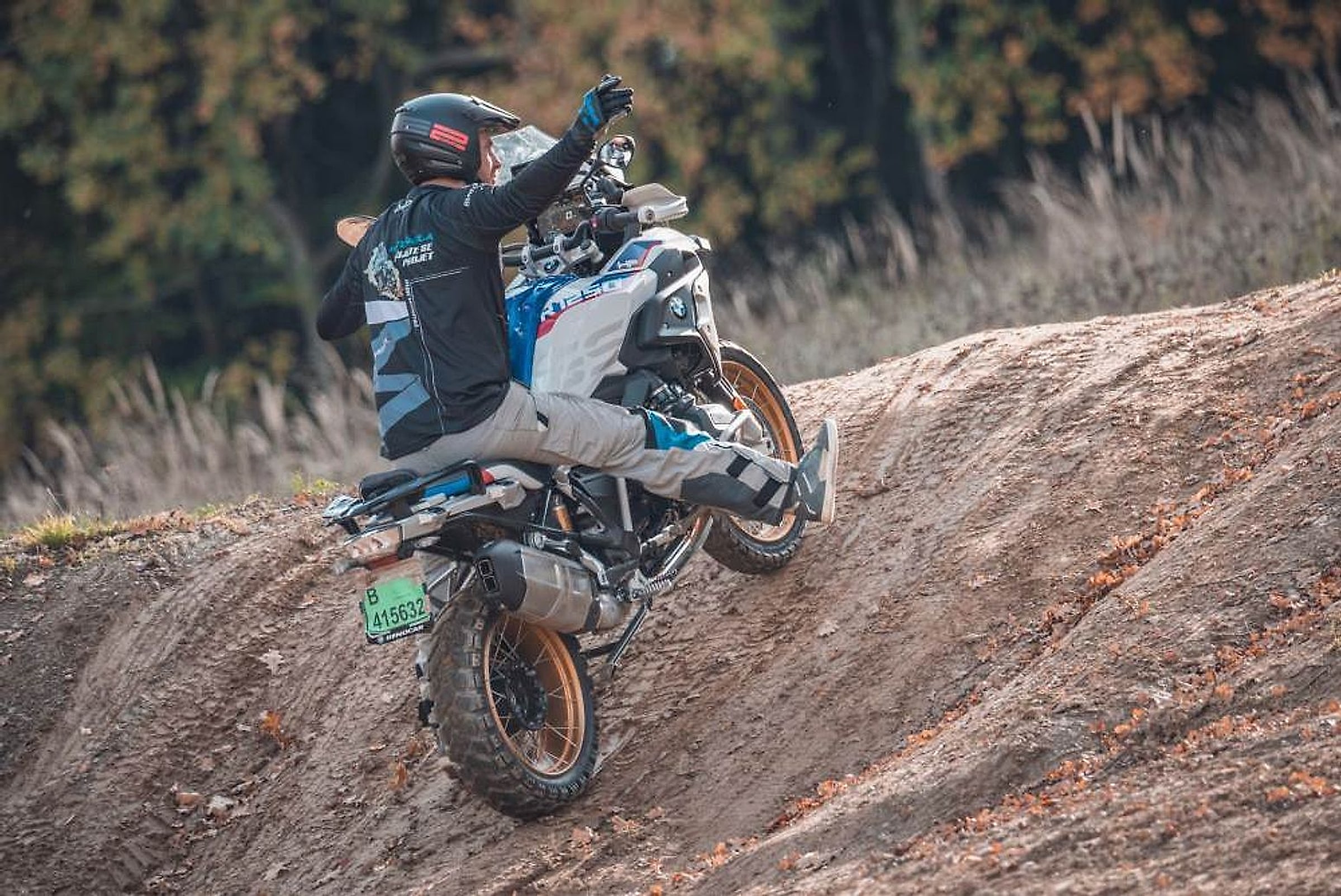 Motorkář na BMW R 1250 GS stoupá po hliněném valu na motokrosové trati