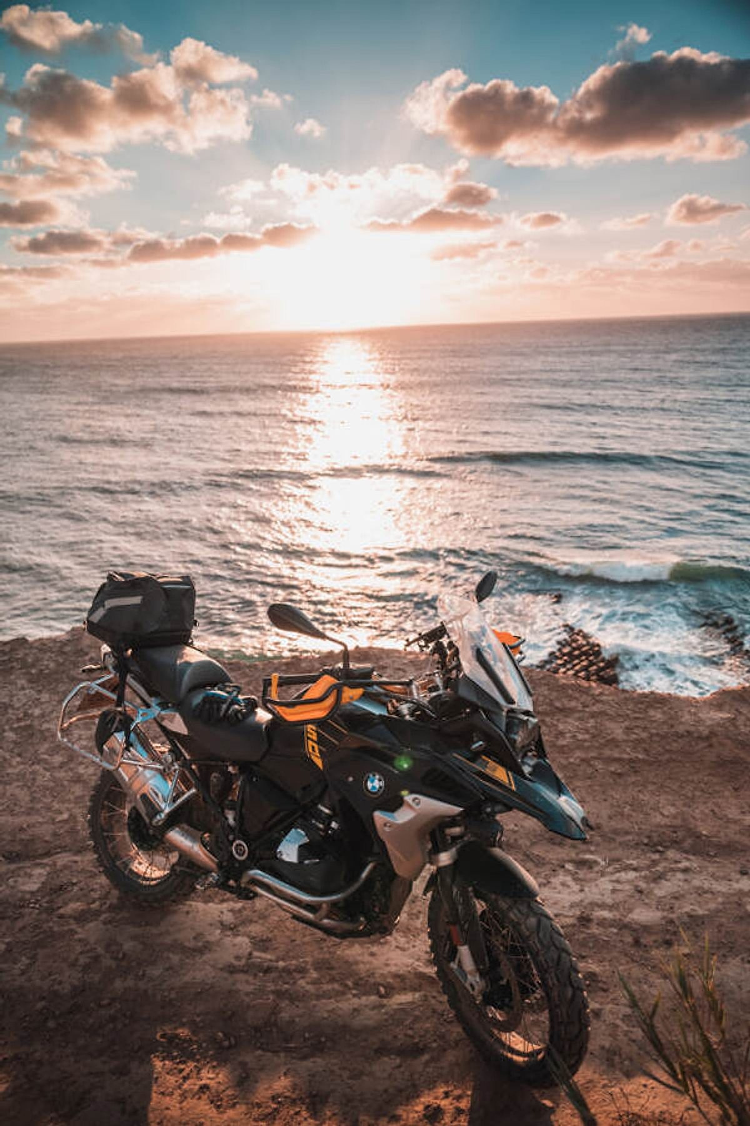 Motorka BMW R 1250 GS zaparkovaná nad oceánem při západu slunce v Portugalsku
