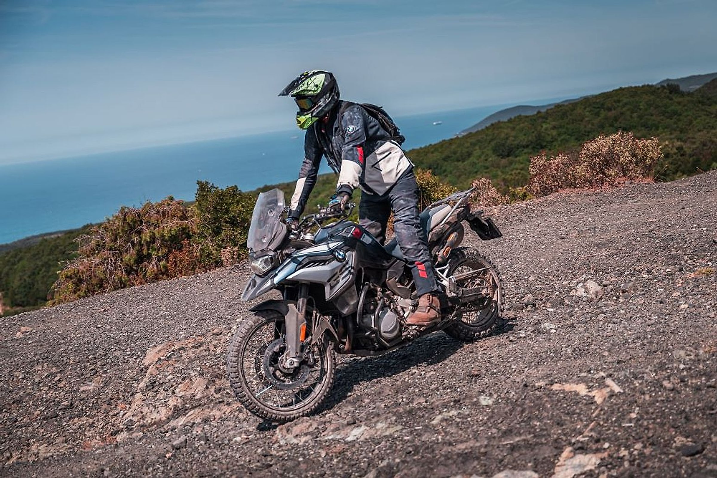 Skupina motorkářů odpočívá u motorek s výhledem do italské krajiny