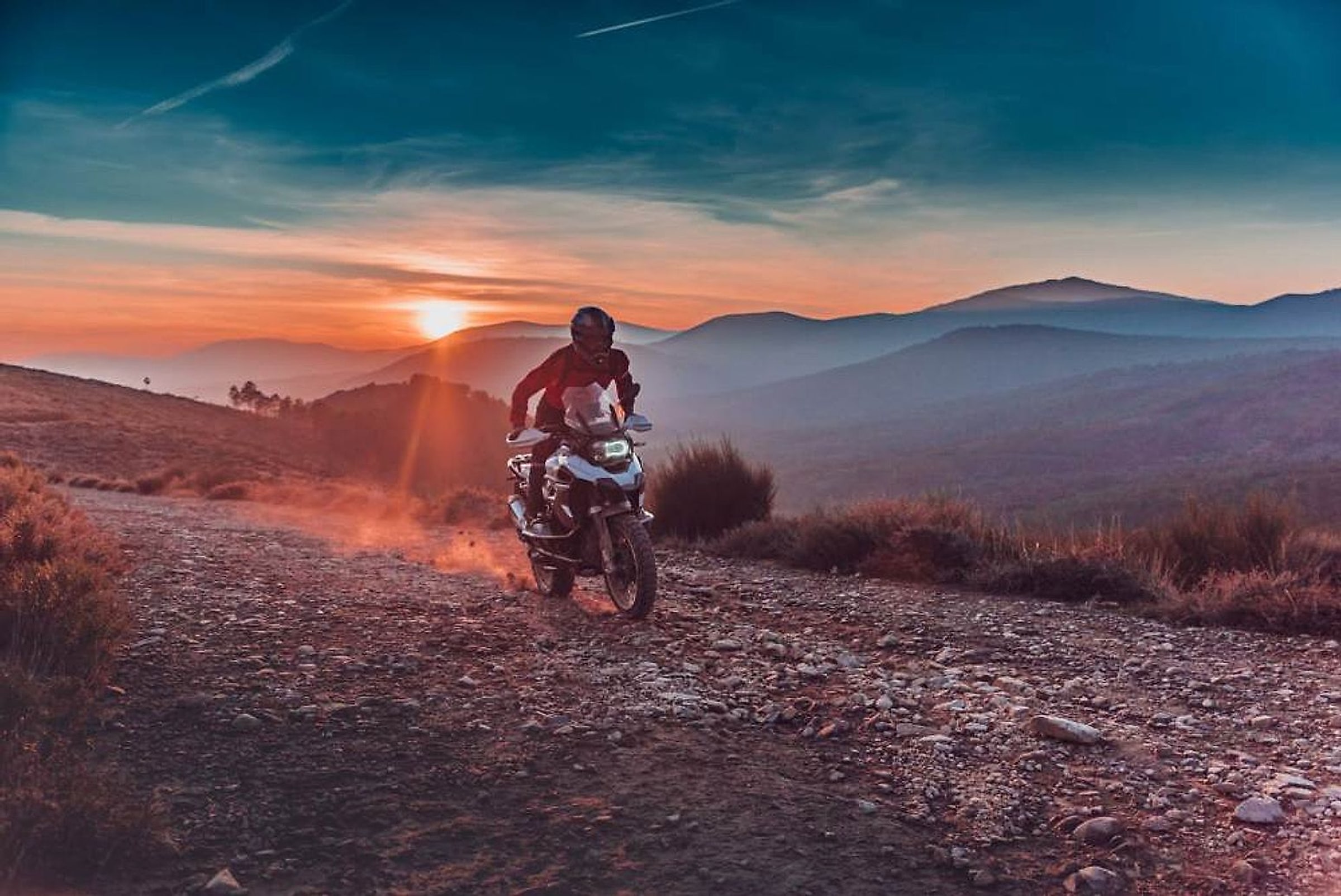 Motorka na kamenité cestě nad španělským údolím v západu slunce