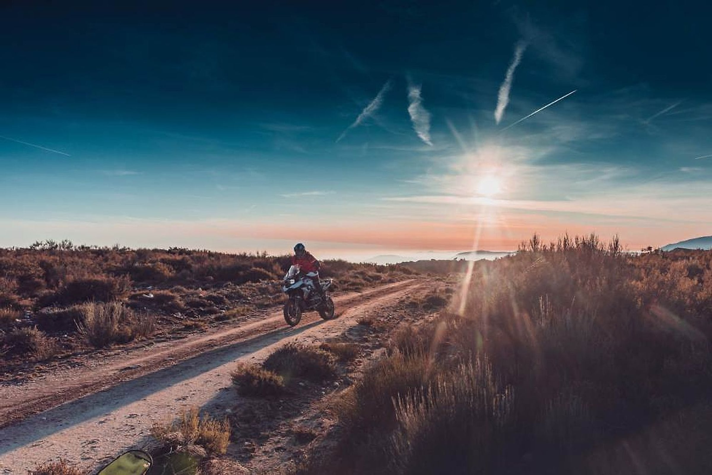 Motorkář na šotolinové cestě ve Španělsku při západu slunce