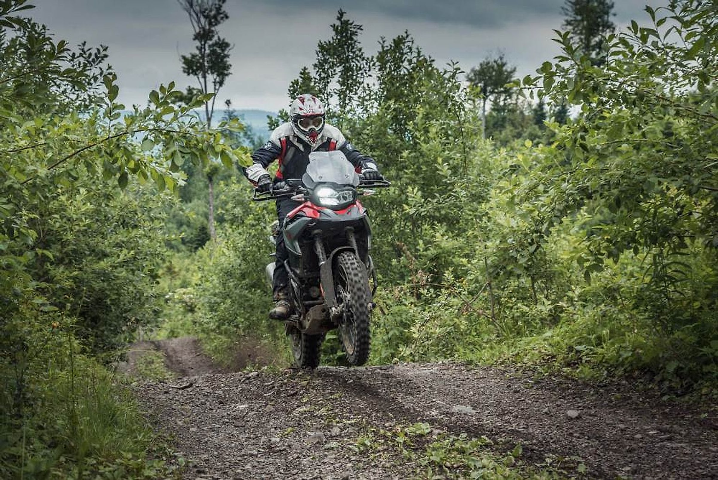 Motorkář na endurové BMW na prašné cestě v horách