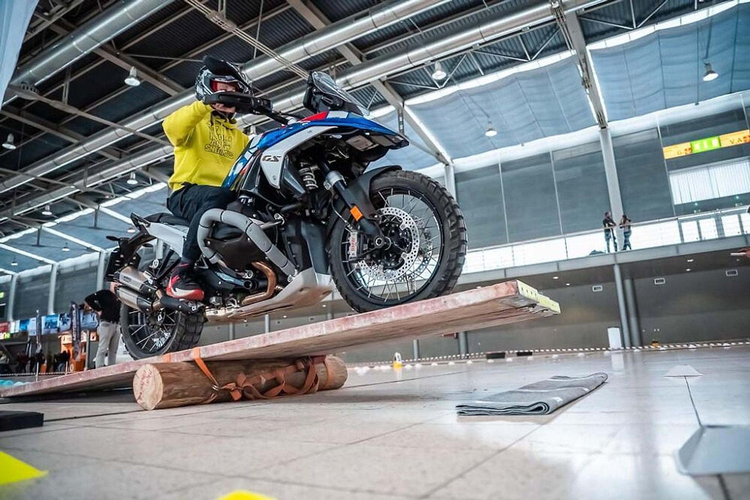 Motorkář na BMW GS najíždí na dřevěnou houpačku v hale Motosalonu